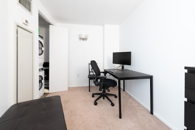 home office featuring stacked washer and clothes dryer and light carpet