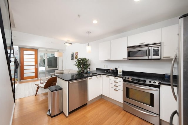 kitchen with pendant lighting, appliances with stainless steel finishes, light hardwood / wood-style floors, white cabinets, and kitchen peninsula