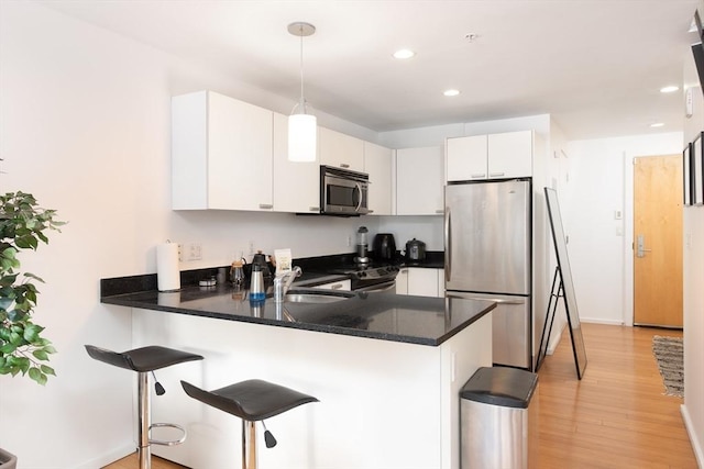 kitchen with pendant lighting, appliances with stainless steel finishes, kitchen peninsula, and sink