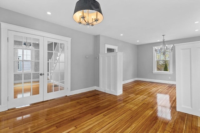 unfurnished dining area with an inviting chandelier, recessed lighting, baseboards, and hardwood / wood-style floors