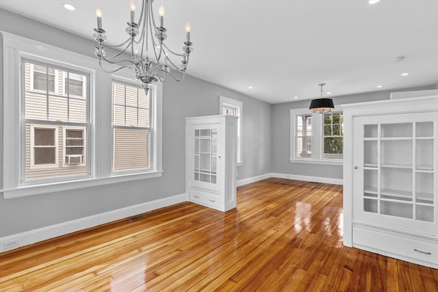 unfurnished dining area with a chandelier, recessed lighting, baseboards, visible vents, and hardwood / wood-style flooring