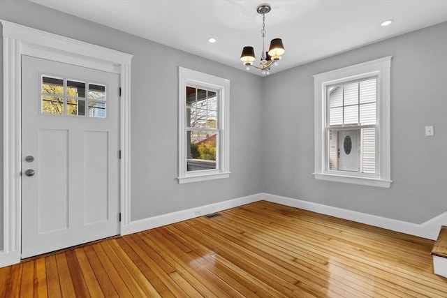 foyer entrance featuring baseboards, a wealth of natural light, and a notable chandelier