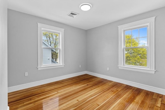 empty room featuring baseboards, visible vents, and light wood finished floors