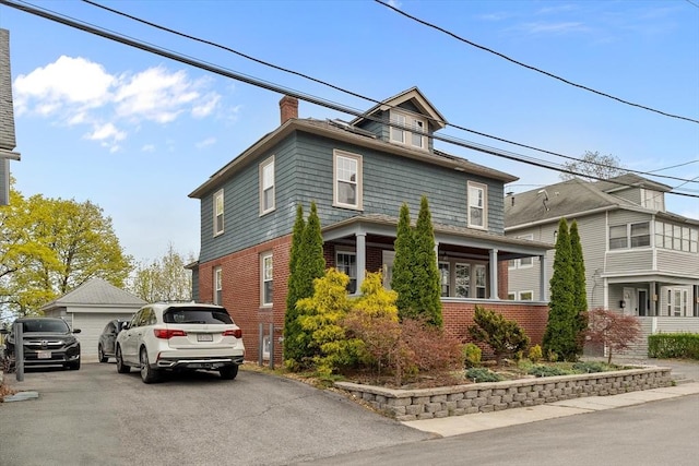 view of front of property with a detached garage, a chimney, and brick siding