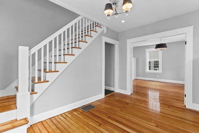 stairway featuring an inviting chandelier, wood-type flooring, recessed lighting, baseboards, and visible vents