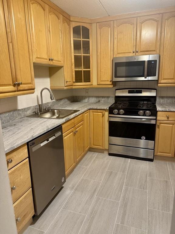 1550 Worcester Rd Unit 503, Framingham, MA 01701 - kitchen featuring stainless steel appliances, a sink, tasteful backsplash, glass insert cabinets, and light brown cabinetry