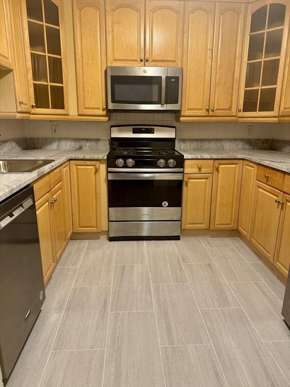1550 Worcester Rd Unit 503, Framingham, MA 01701 - kitchen with stainless steel appliances, a sink, glass insert cabinets, and light stone counters