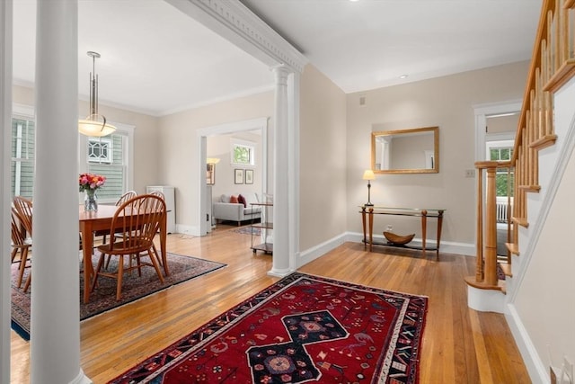 50-52 Linden Pl, Brookline, MA 02446 - entrance foyer featuring light wood-style floors, baseboards, stairs, ornamental molding, and ornate columns