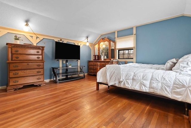 bedroom featuring baseboards, lofted ceiling, and wood finished floors