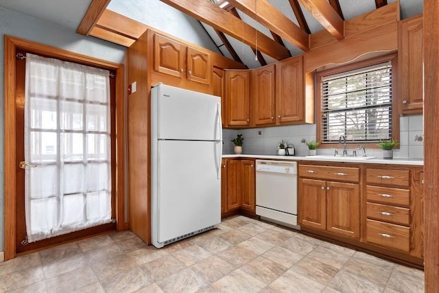 kitchen with white appliances, brown cabinetry, vaulted ceiling with beams, a sink, and light countertops