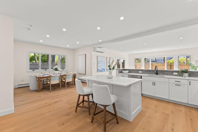 354 Gifford Unit 1, Falmouth, MA 02540 - kitchen featuring a baseboard radiator, an AC wall unit, a sink, a center island, and light wood-type flooring