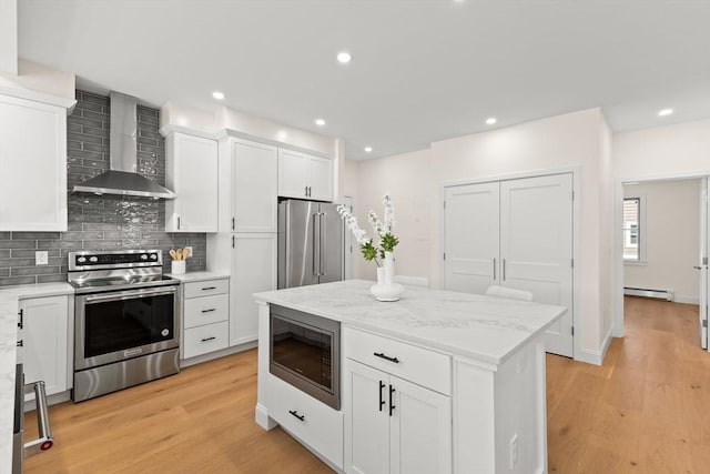 354 Gifford Unit 1, Falmouth, MA 02540 - kitchen featuring wall chimney exhaust hood, appliances with stainless steel finishes, baseboard heating, backsplash, and light wood-style flooring