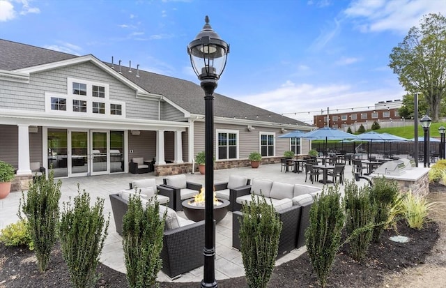 back of property with roof with shingles, an outdoor living space with a fire pit, a patio, and fence