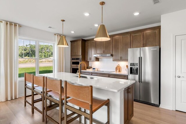 kitchen featuring light wood-type flooring, stainless steel refrigerator with ice dispenser, black electric stovetop, and a sink