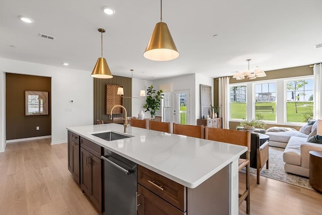 kitchen with a sink, open floor plan, light wood-style floors, dishwasher, and visible vents
