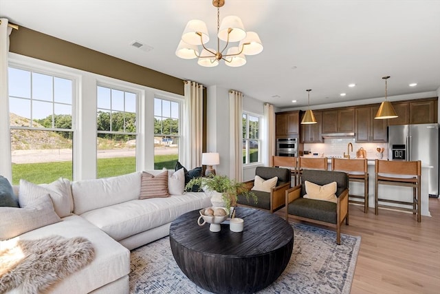 living room featuring recessed lighting, visible vents, an inviting chandelier, and light wood-style floors