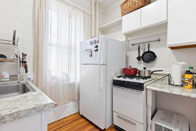 kitchen with white appliances, white cabinetry, light countertops, light wood finished floors, and a sink