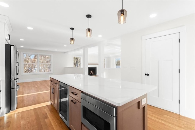 kitchen featuring white cabinets, beverage cooler, hanging light fixtures, a center island, and stainless steel appliances