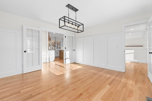 unfurnished dining area featuring an inviting chandelier and light wood-type flooring