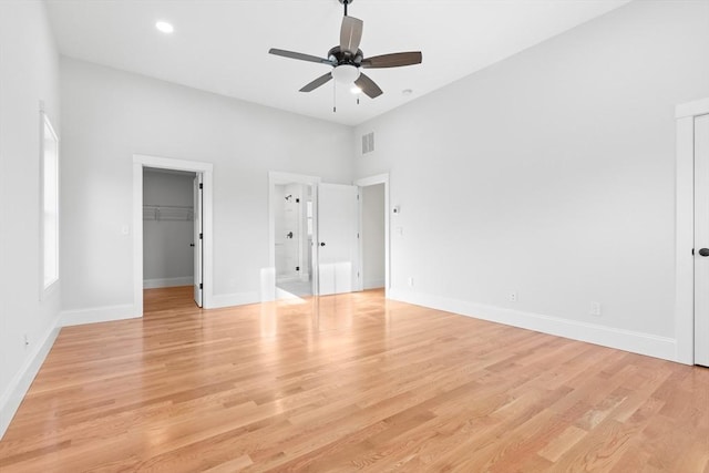 unfurnished bedroom with a spacious closet, light hardwood / wood-style flooring, a closet, and ceiling fan