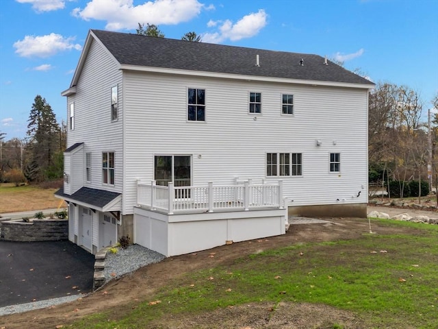 back of house with a garage, a wooden deck, and a yard