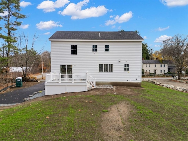 back of property featuring a deck and a lawn