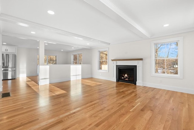 unfurnished living room featuring ornamental molding, beam ceiling, and light hardwood / wood-style flooring