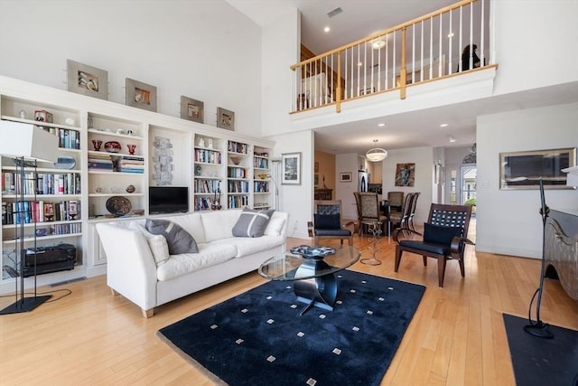 living area with a high ceiling, visible vents, and hardwood / wood-style flooring