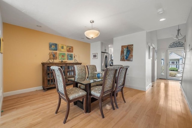 dining space with baseboards and light wood-style flooring