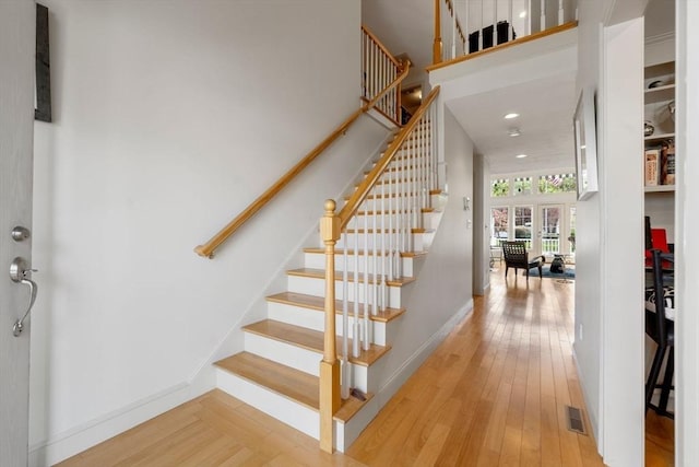 staircase with baseboards, a high ceiling, and hardwood / wood-style floors