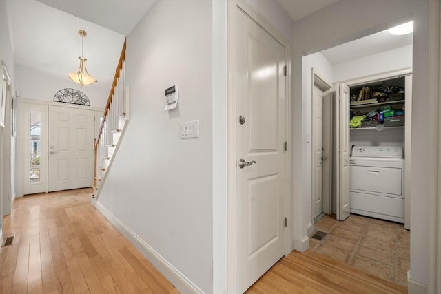 foyer entrance with visible vents, washer / dryer, stairs, light wood-style floors, and baseboards