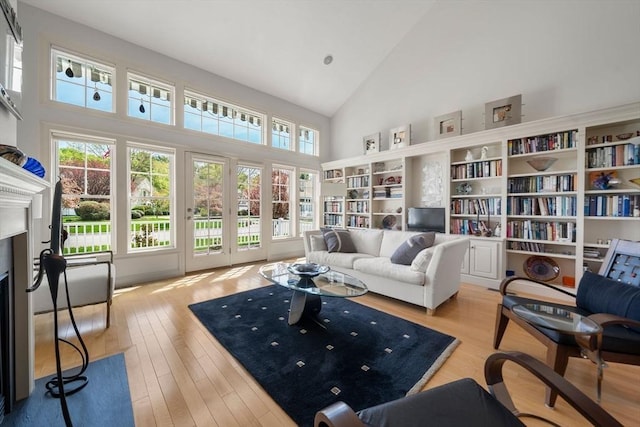 living area featuring a fireplace with flush hearth, high vaulted ceiling, and wood finished floors