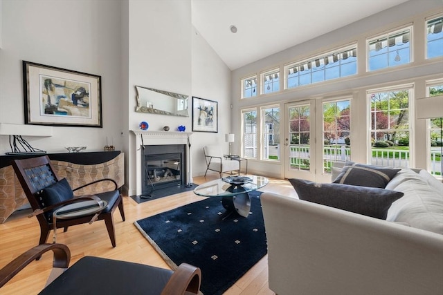 living room featuring a fireplace with flush hearth, high vaulted ceiling, french doors, and a wealth of natural light