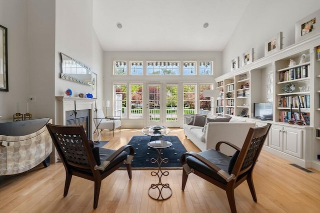 sitting room featuring high vaulted ceiling, visible vents, light wood-style flooring, and a fireplace