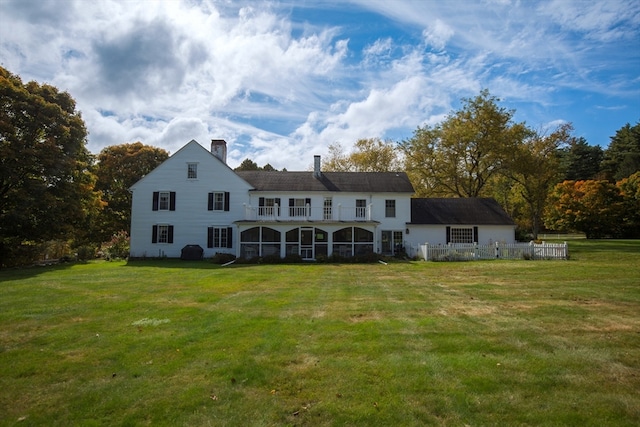 rear view of house with a lawn and a balcony