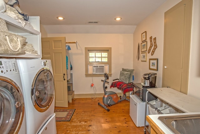 washroom with cabinets, light wood-type flooring, washing machine and dryer, and cooling unit