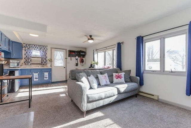 carpeted living room with ceiling fan, sink, and a baseboard radiator