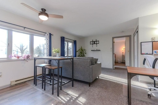 living room featuring light hardwood / wood-style flooring, ceiling fan, and a baseboard heating unit