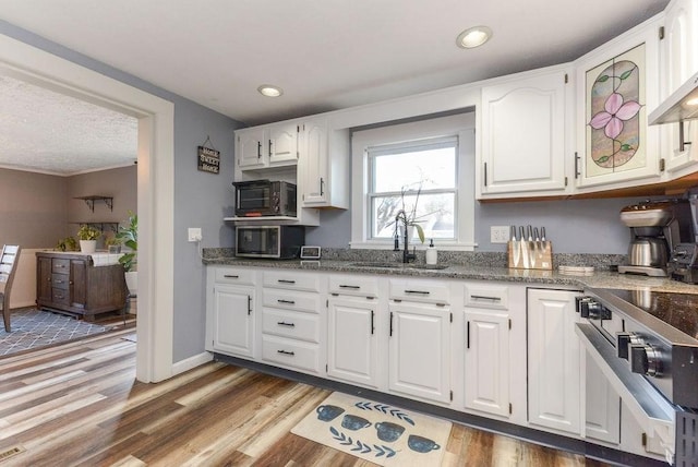 kitchen featuring white cabinetry, sink, dark stone counters, and light hardwood / wood-style flooring