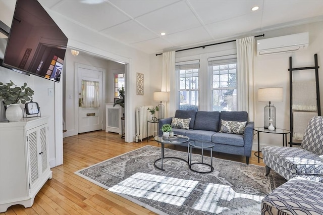 living area featuring recessed lighting, a wall mounted air conditioner, light wood finished floors, and radiator heating unit