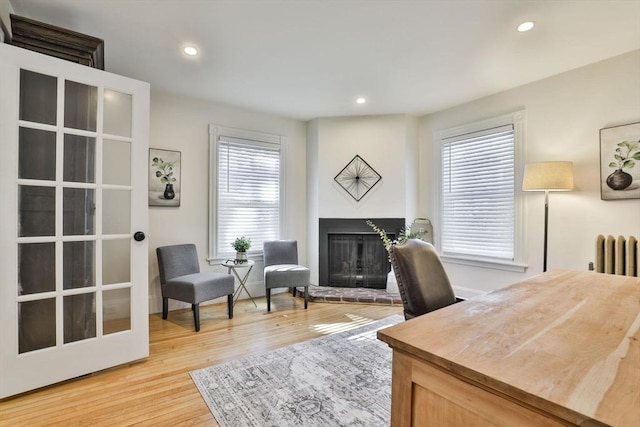 home office with radiator, light wood finished floors, recessed lighting, and a glass covered fireplace