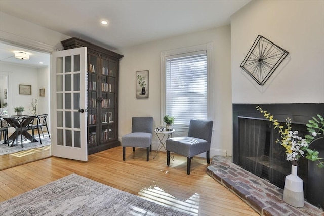 sitting room with french doors, hardwood / wood-style floors, a fireplace, and recessed lighting