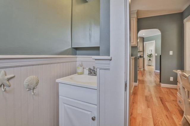 bathroom featuring wainscoting, crown molding, vanity, and wood finished floors