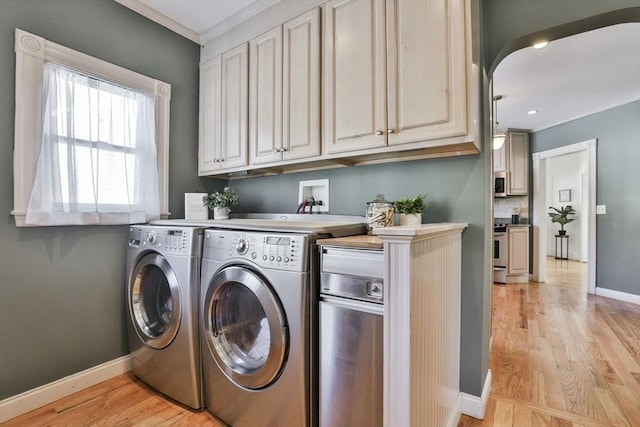 clothes washing area featuring ornamental molding, washer and clothes dryer, cabinet space, and baseboards