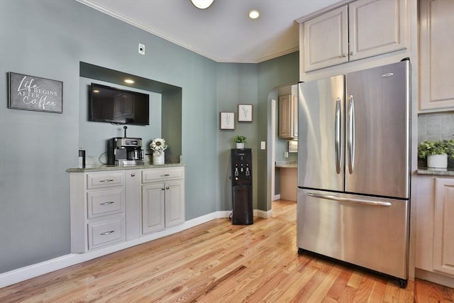 kitchen featuring ornamental molding, light wood-style flooring, freestanding refrigerator, and baseboards