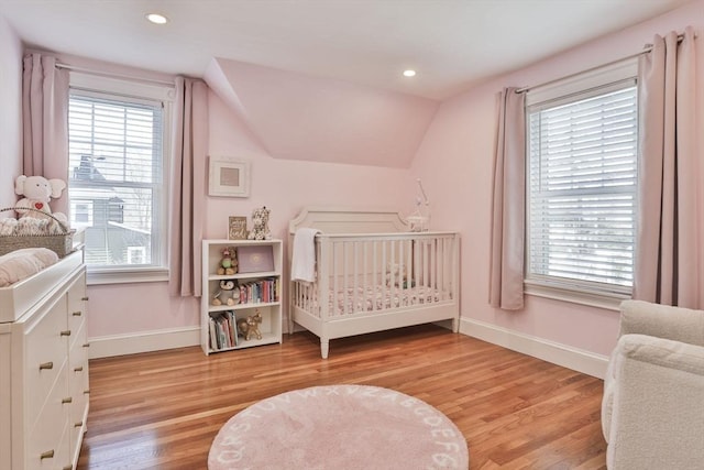 bedroom featuring lofted ceiling, multiple windows, light wood-style flooring, and baseboards