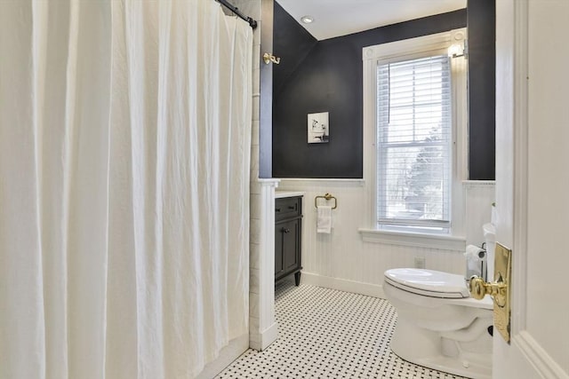 full bathroom with curtained shower, wainscoting, vanity, and toilet