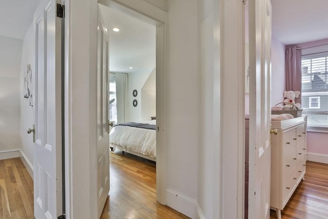 hallway featuring light wood-type flooring and baseboards