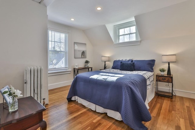 bedroom with recessed lighting, wood finished floors, baseboards, vaulted ceiling, and radiator