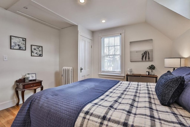 bedroom with recessed lighting, radiator, lofted ceiling, wood finished floors, and baseboards